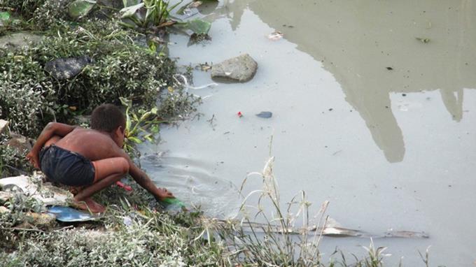 A boy playing near the river