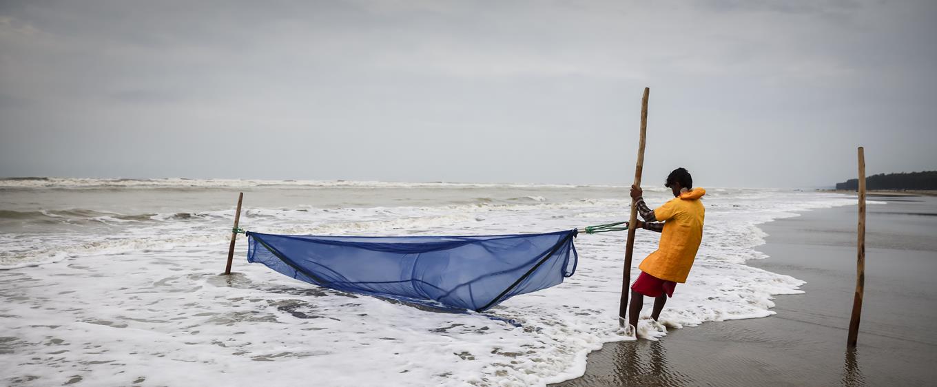 Boy pulling in a fihsing boat from the sea